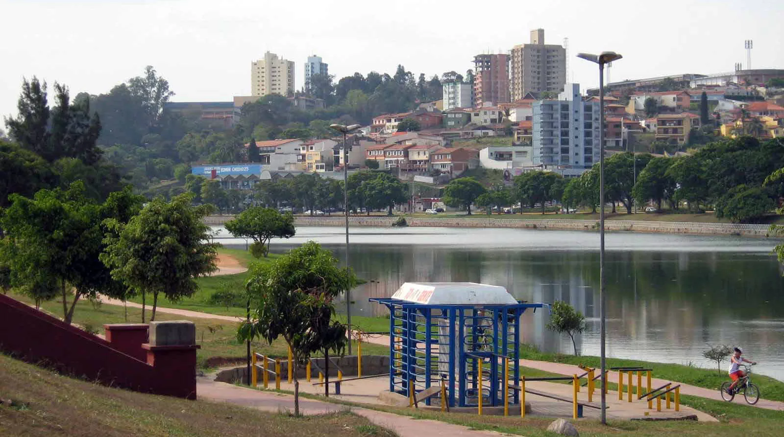 Vista de Bragança Paulista a partir do Lago do Taboão, com área de ginástica e morro com casas ao fundo