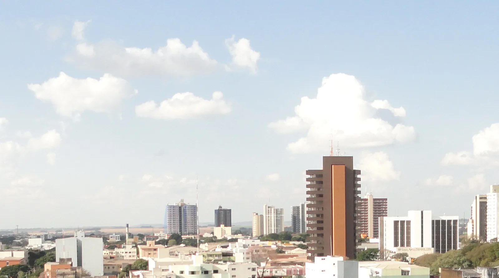Vista do centro de Campo Mourão, no Paraná, com edifícios e árvores sob céu azul