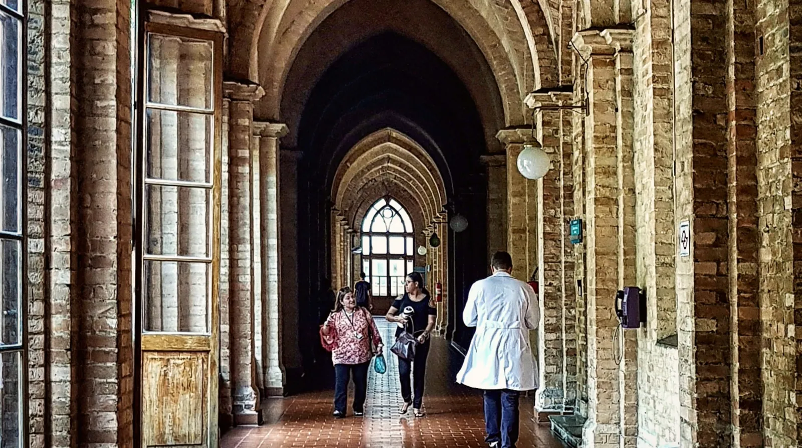 Corredor de arcos do Hospital Central da Santa Casa de Misericórdia de São Paulo, com médico de jaleco branco caminhando